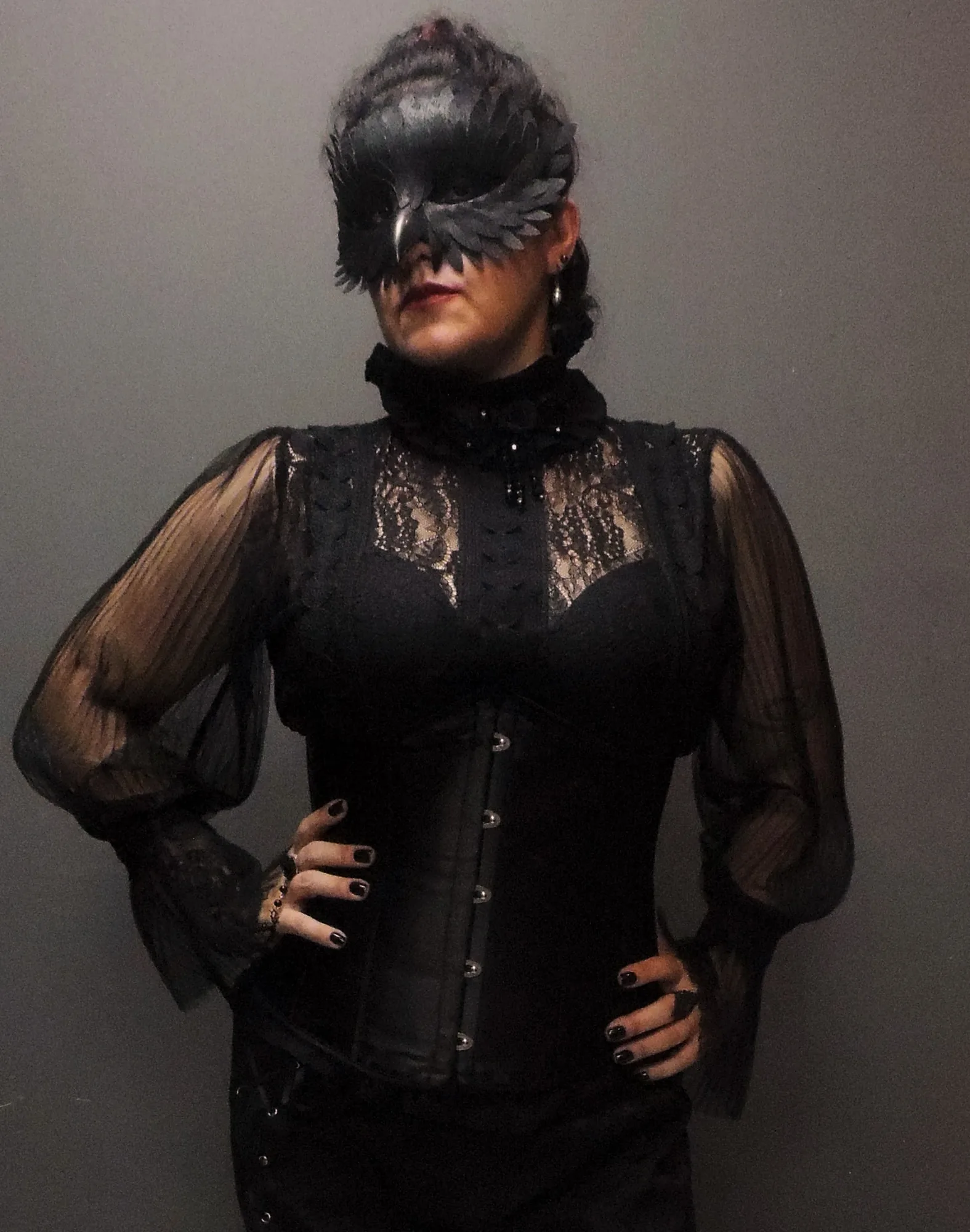 The Countess usando máscara de corvo e traje preto
