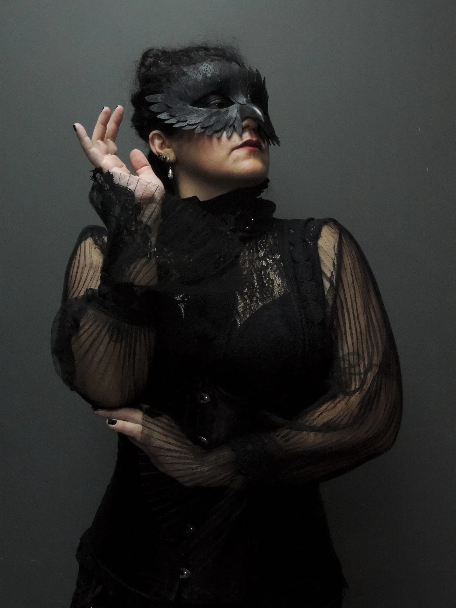The Countess usando máscara de corvo e traje preto